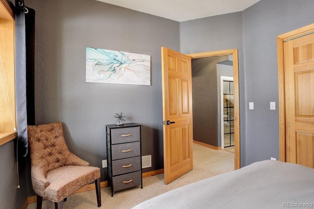 bedroom with visible vents, baseboards, light colored carpet, and a textured wall