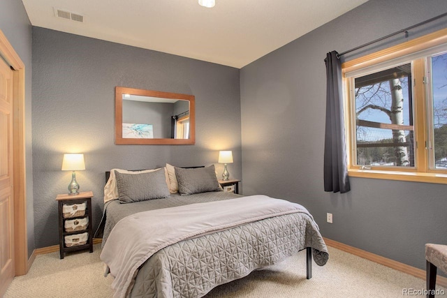 bedroom featuring carpet flooring, visible vents, baseboards, and a textured wall