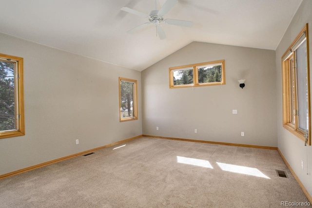 carpeted empty room with visible vents, baseboards, ceiling fan, and vaulted ceiling