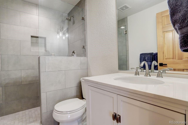 bathroom featuring visible vents, toilet, walk in shower, and vanity