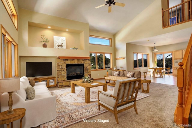 living room featuring baseboards, high vaulted ceiling, a stone fireplace, and a ceiling fan