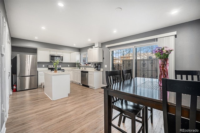 kitchen featuring light wood finished floors, white cabinetry, stainless steel appliances, and light countertops