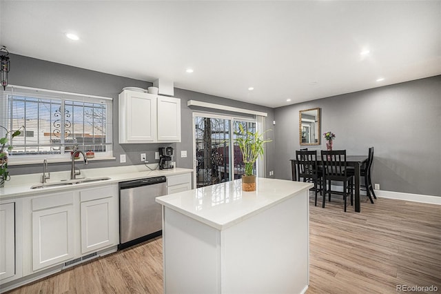 kitchen with dishwasher, light countertops, a sink, and light wood-style floors