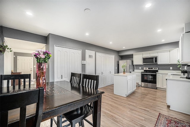 kitchen featuring a center island, stainless steel appliances, light countertops, light wood-style floors, and recessed lighting