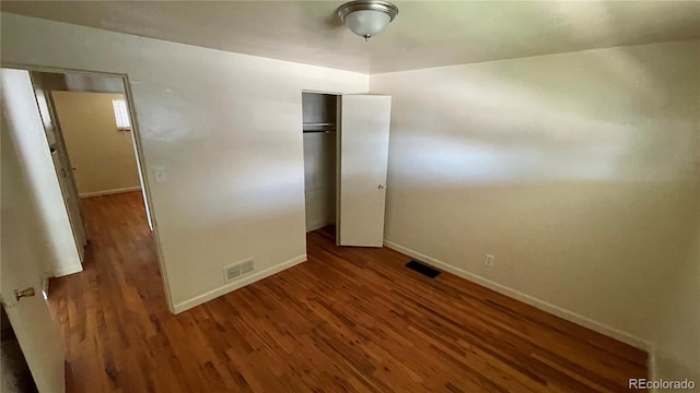 unfurnished bedroom with a closet and dark hardwood / wood-style flooring