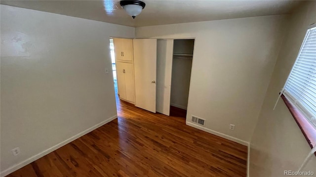 unfurnished bedroom featuring a closet and dark hardwood / wood-style floors