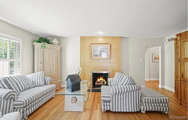 6235 E 6th Avenue Parkway, Denver, CO 80220 - living room featuring a tiled fireplace, visible vents, light wood-style flooring, and baseboards