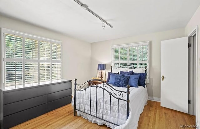 6235 E 6th Avenue Parkway, Denver, CO 80220 - bedroom with track lighting, multiple windows, wood finished floors, and baseboards