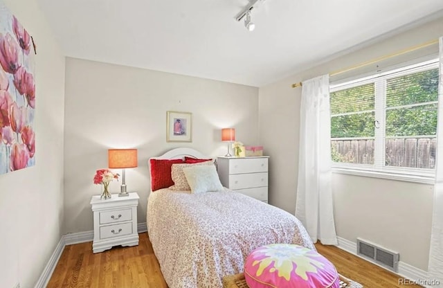 6235 E 6th Avenue Parkway, Denver, CO 80220 - bedroom featuring rail lighting, baseboards, visible vents, and wood finished floors