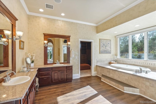 bathroom featuring vanity, hardwood / wood-style floors, ornamental molding, and tiled tub