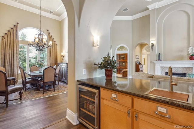 kitchen with a tiled fireplace, dark hardwood / wood-style flooring, beverage cooler, sink, and decorative light fixtures