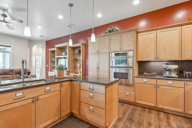 kitchen featuring sink, ceiling fan, hanging light fixtures, hardwood / wood-style floors, and double oven