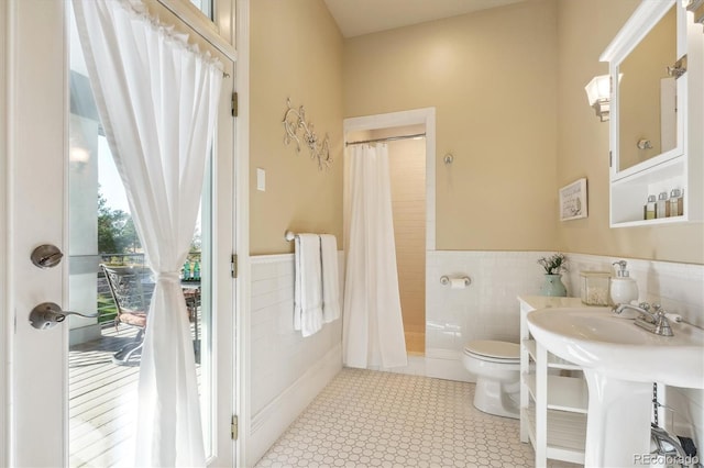 bathroom with toilet, tile walls, and curtained shower