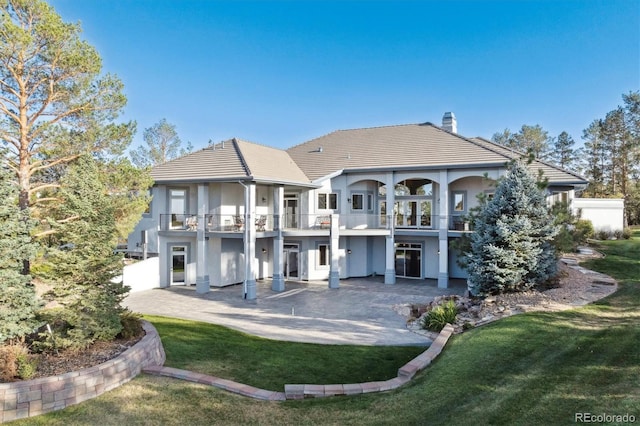 rear view of house featuring a patio, a lawn, and a balcony