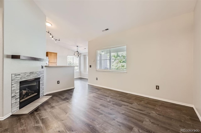 unfurnished living room with lofted ceiling, dark hardwood / wood-style floors, an inviting chandelier, and a fireplace