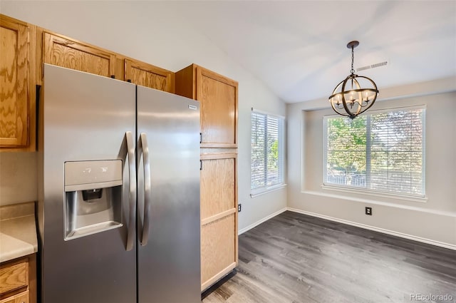 kitchen featuring wood-type flooring, decorative light fixtures, vaulted ceiling, stainless steel fridge, and a notable chandelier