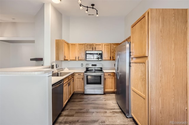 kitchen with appliances with stainless steel finishes, sink, dark hardwood / wood-style flooring, kitchen peninsula, and light brown cabinets