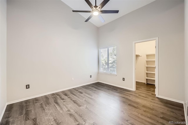 unfurnished bedroom with ceiling fan, high vaulted ceiling, dark hardwood / wood-style floors, a walk in closet, and a closet