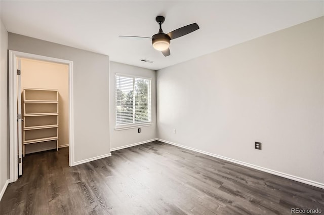 unfurnished bedroom featuring ceiling fan, a spacious closet, dark hardwood / wood-style floors, and a closet