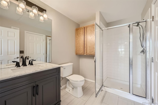 bathroom featuring toilet, vanity, and a shower with shower door