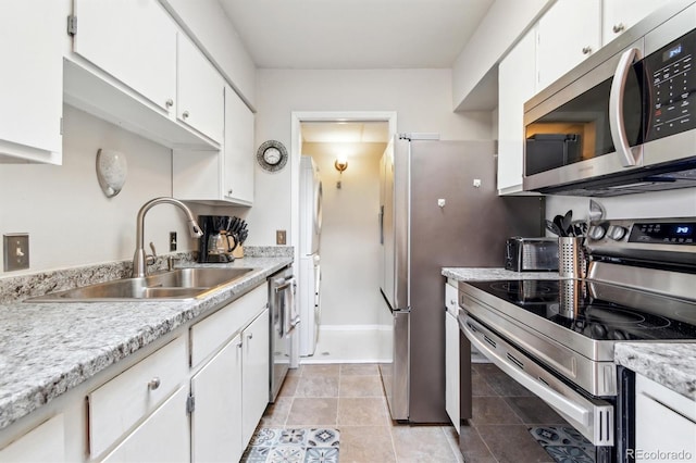 kitchen with light tile patterned floors, a sink, white cabinetry, light countertops, and appliances with stainless steel finishes