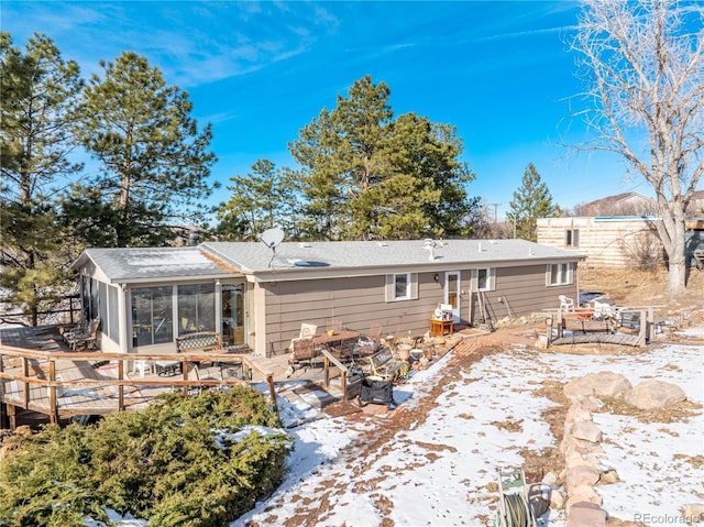 snow covered house featuring a sunroom and a deck