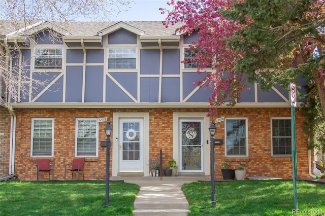 multi unit property featuring a front lawn and brick siding