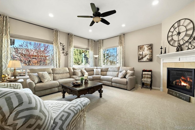 living room with a fireplace, light colored carpet, and ceiling fan