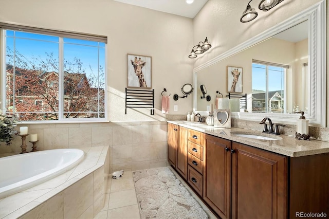 bathroom with tile patterned floors, vanity, and a relaxing tiled tub