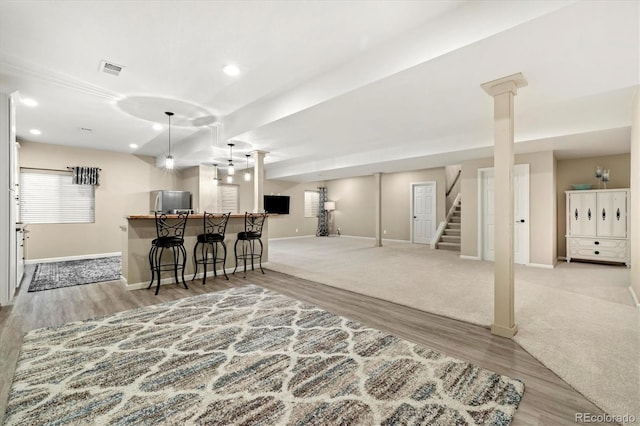 interior space featuring a breakfast bar area, kitchen peninsula, stainless steel refrigerator, and light hardwood / wood-style floors