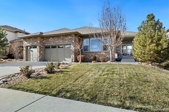 prairie-style home featuring a garage, stone siding, a front yard, and concrete driveway
