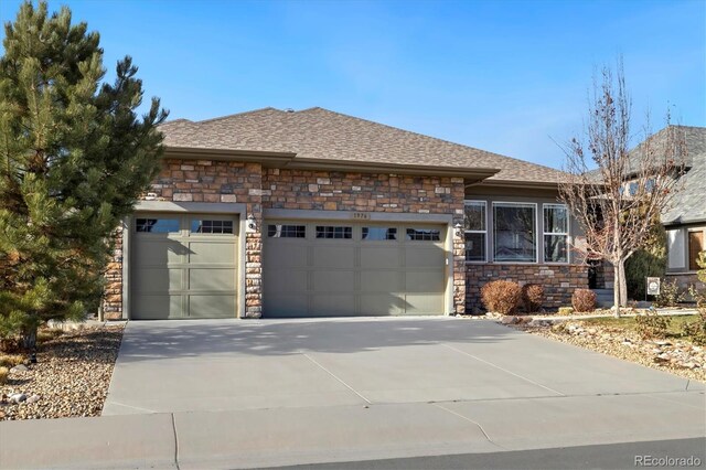 view of front of home with concrete driveway, an attached garage, roof with shingles, and stone siding