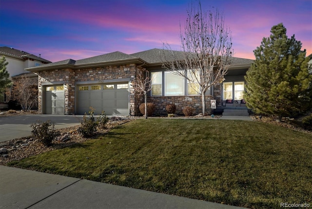 ranch-style house featuring an attached garage, a yard, stone siding, and concrete driveway