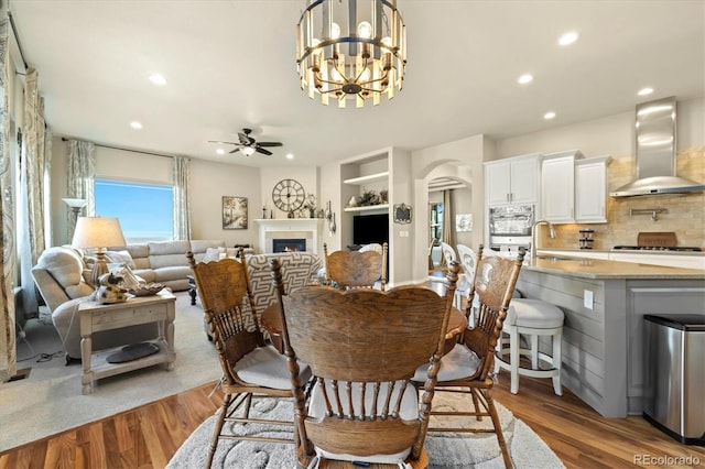 dining area featuring recessed lighting, arched walkways, wood finished floors, and ceiling fan with notable chandelier