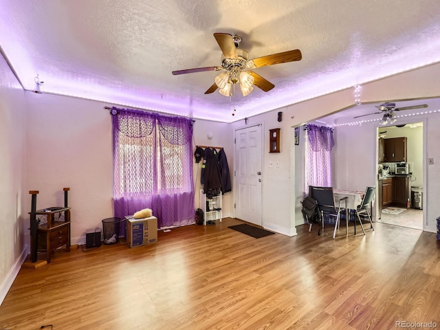 interior space featuring ceiling fan, wood-type flooring, and a textured ceiling