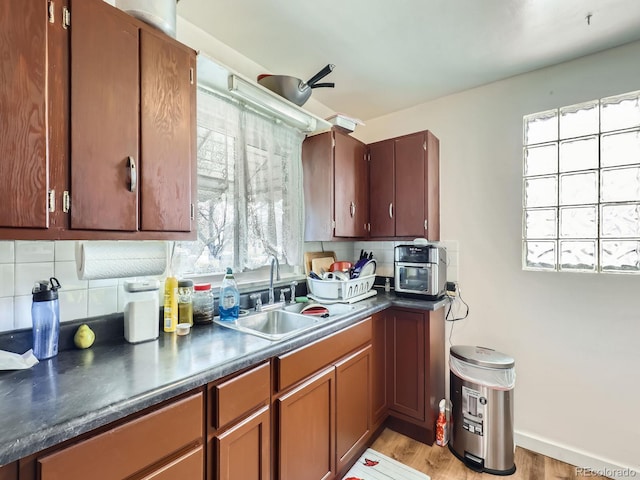 kitchen with sink, decorative backsplash, and light wood-type flooring