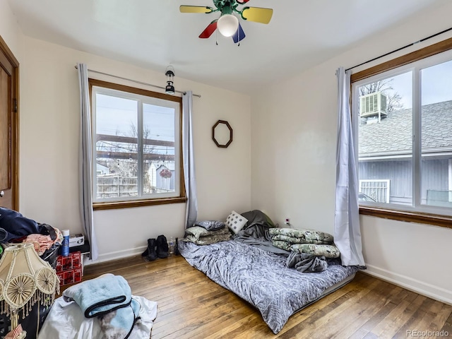 bedroom featuring hardwood / wood-style flooring, ceiling fan, and multiple windows