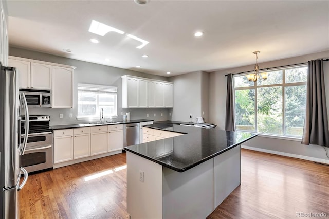 4630 Whitehall Ln, Highlands Ranch, CO 80126 - kitchen featuring stainless steel appliances, light wood finished floors, white cabinetry, recessed lighting, and a chandelier