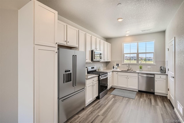 kitchen featuring white cabinets, light wood-type flooring, stainless steel appliances, and sink