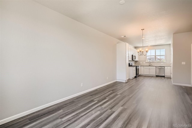 unfurnished living room with sink, wood-type flooring, and an inviting chandelier