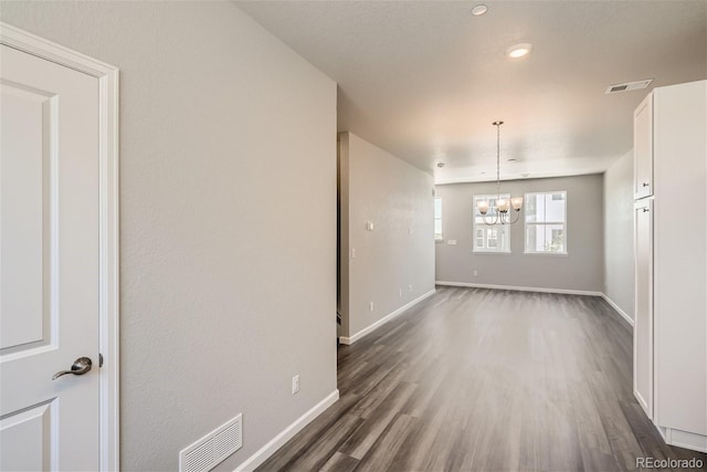 empty room featuring a chandelier and dark wood-type flooring