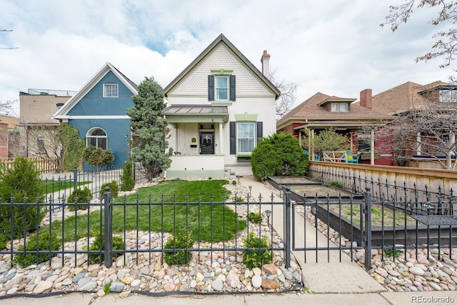 victorian-style house featuring a fenced front yard, covered porch, and stucco siding