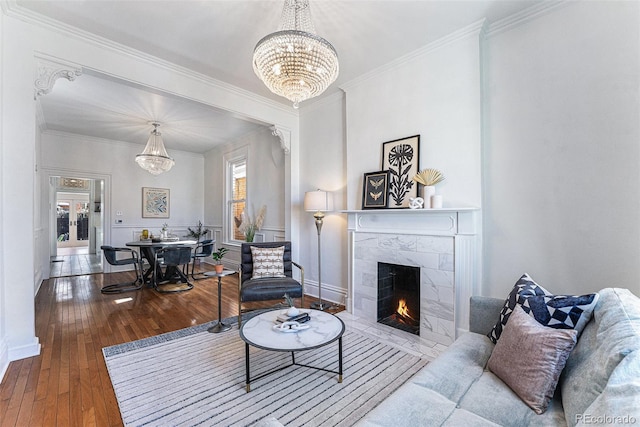 living room featuring an inviting chandelier, a fireplace, wood-type flooring, and ornamental molding