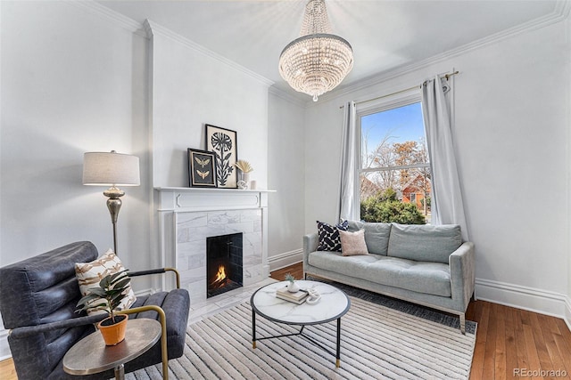 living room featuring a tiled fireplace, baseboards, hardwood / wood-style floors, and ornamental molding