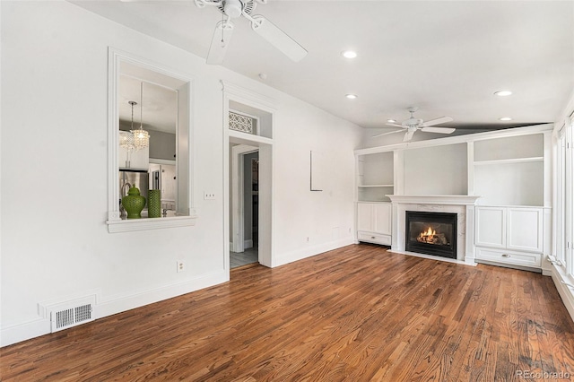 unfurnished living room with visible vents, a fireplace with flush hearth, ceiling fan, and wood finished floors