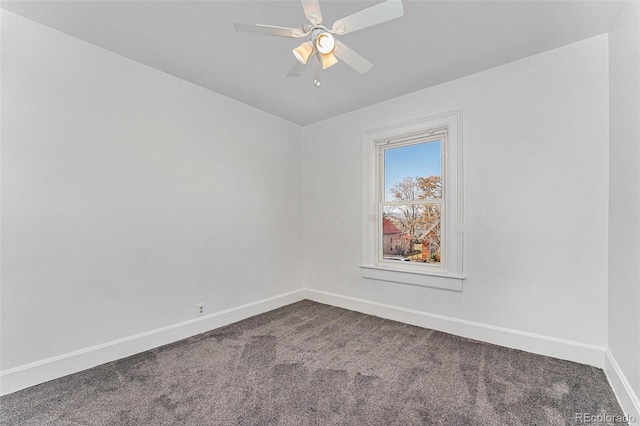 spare room with ceiling fan, baseboards, and dark colored carpet