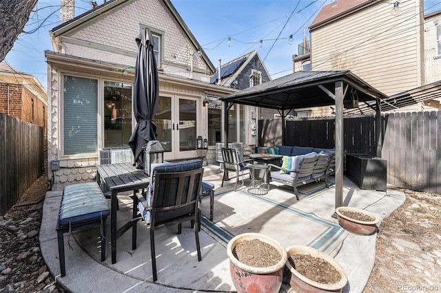 view of patio featuring an outdoor living space, a gazebo, french doors, a fenced backyard, and outdoor dining space