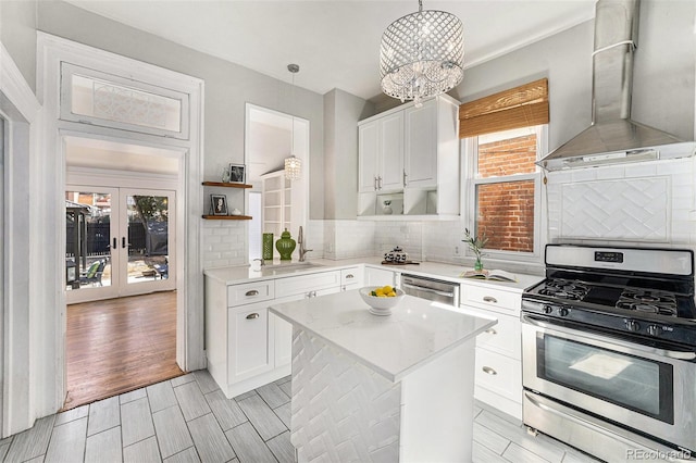 kitchen featuring a sink, appliances with stainless steel finishes, wall chimney exhaust hood, white cabinets, and light countertops