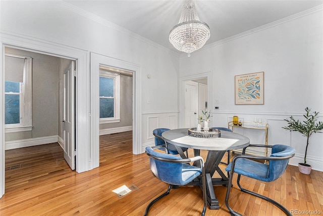 dining room featuring a chandelier, visible vents, light wood finished floors, and crown molding