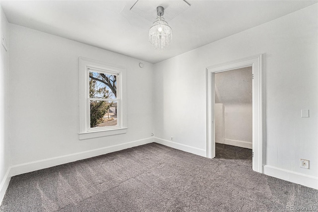 unfurnished bedroom featuring dark colored carpet, baseboards, and an inviting chandelier